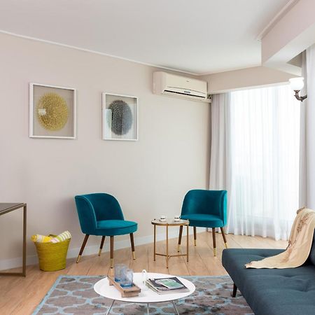 โรงแรมลีโอนาร์โด คลับ เดด ซี ออล อินคลูซีฟ เนเว โซฮาร์ ภายนอก รูปภาพ The photo depicts a modern living room setting. The room features a dark blue sofa with a light throw blanket draped over it. There are two stylish teal accent chairs positioned around a small round coffee table, which holds various items. A flat-scr
